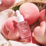 زجاجة سيروم Anua Peach 70 Niacin موضوعة بين حبات الخوخ